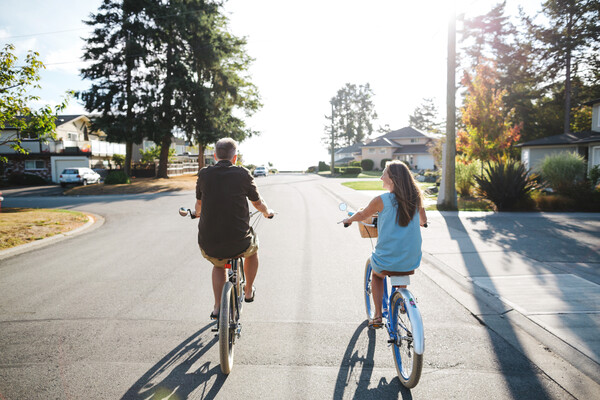 young couple riding cruiser bikes through a neighbourhood